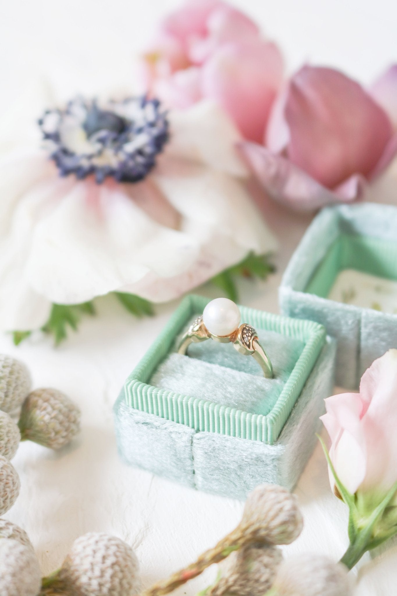 The Luna Diamond and Pearl Vintage Engagement Ring in 9ct Gold in a ring box surrounded by flowers. Canadian jewelry designs. Antique Engagement Rings Canada. Canadian vintage engagement rings. Vintage engagement rings Canada. Bridal jewelry Canada. Pearl jewelry Canada. Pearl Bridal jewelry Canada. Canadian jewelry brands. Organic pearl jewelry.