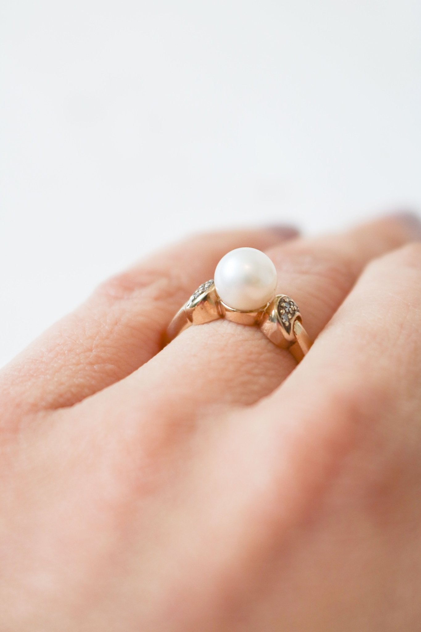 Close up side view of a gold and pearl vintage engagement ring with diamonds on a ring finger. Canadian jewelry designs. Antique Engagement Rings Canada. Canadian vintage engagement rings. Vintage engagement rings Canada. Bridal jewelry Canada. Pearl jewelry Canada. Pearl Bridal jewelry Canada. Canadian jewelry brands. Organic pearl jewelry.