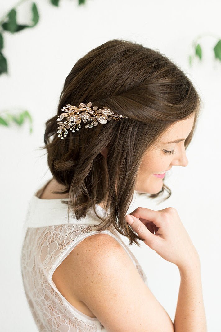 Bride in white lacey wedding dress with elegant rose gold floral leaf bridal hair accessory with Swarovski crystals against a blurred withe background with greenery. Handmade wedding accessories & bridal hair accessories Canada