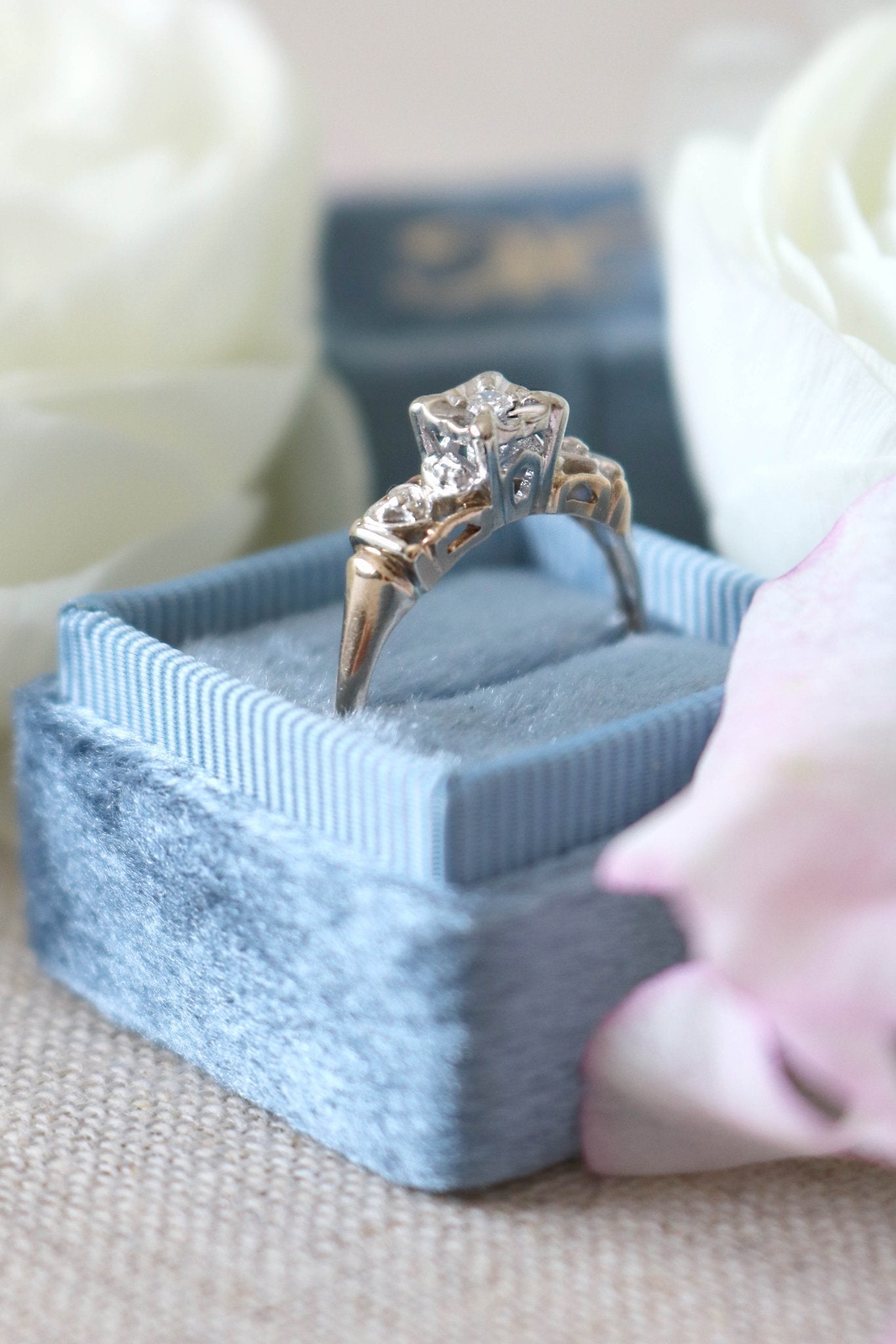 A close up side view of the Melisma Art Deco Diamond Heart Engagement Ring in 14ct Yellow and White Gold in a blue ring box. Antique Engagement Rings Canada. Canadian vintage engagement rings. Vintage engagement rings Canada. Bridal jewelry Canada. Canadian weddings. Wedding Canada. Canadian bridal jewelry. Woman-owned Canadian jewelry brand. Canadian jewelry business.