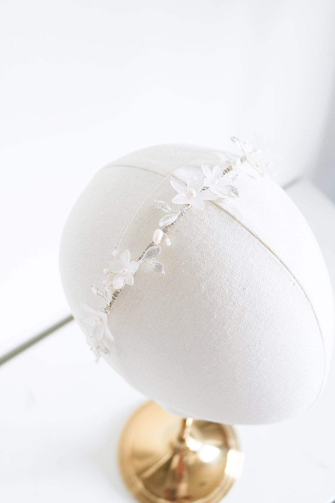 A silver bridal headband with freshwater pearls and light florals on a head bust. Bridal Hair Accessories. Bridal Accessories. Canadian Bridal Accessories. Handmade Canadian Accessories. Canadian handmade Accessories. Organic pearl accessories. Canadian weddings. Wedding Canada.