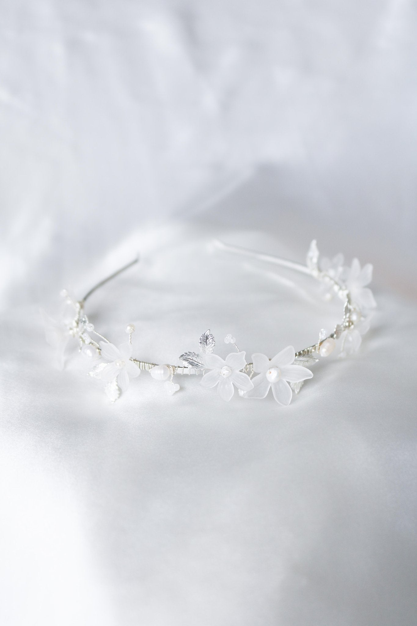 A silver floral bridal headband with organic freshwater pearls laying on a satin sheet. Bridal Hair Accessories. Bridal Accessories. Canadian Bridal Accessories. Handmade Canadian Accessories. Canadian handmade Accessories. Organic pearl accessories. Canadian weddings. Wedding Canada.