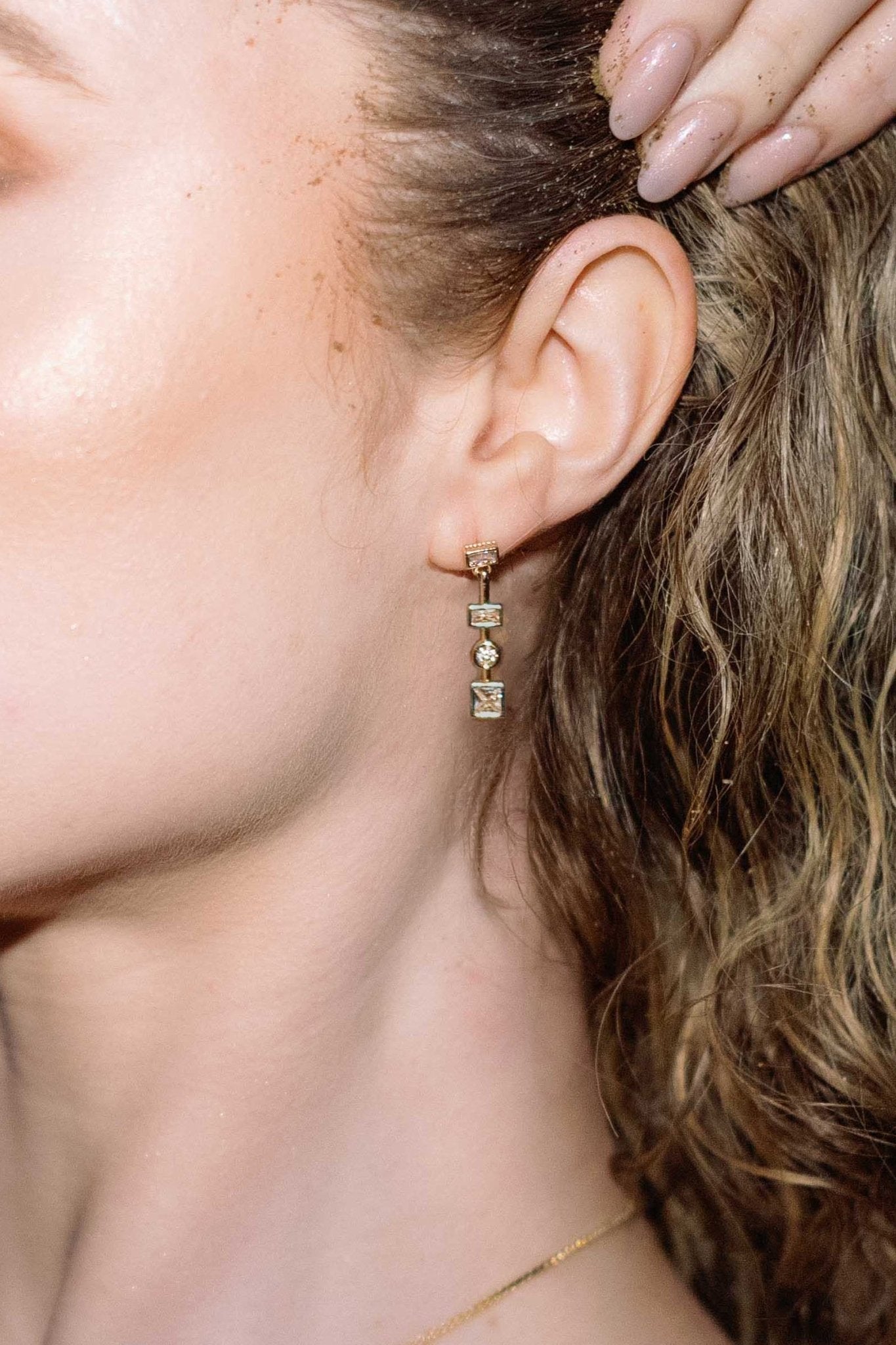 Close-up of an ear wearing a gold-filled earring with three small crystals. Statement Earrings. Statement Bridal Earrings. Affordable Canadian jewelry brands. Gold-filled Canadian jewelry