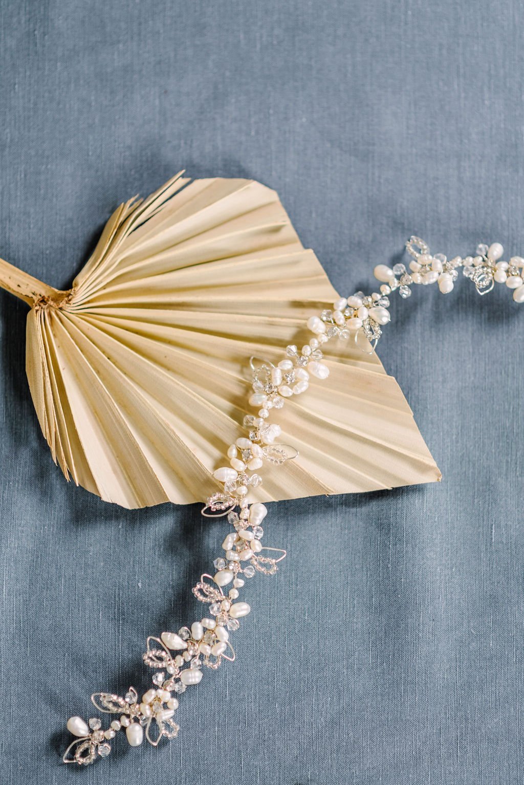 The Nevah Floral Fresh Water Pearl and Crystal Hairvine lays across a golden leaf on a blue background. Bridal Hair Accessories. Bridal Accessories. Canadian Bridal Accessories. Handmade Canadian Accessories. Canadian handmade Accessories. Canadian weddings. Wedding Canada.