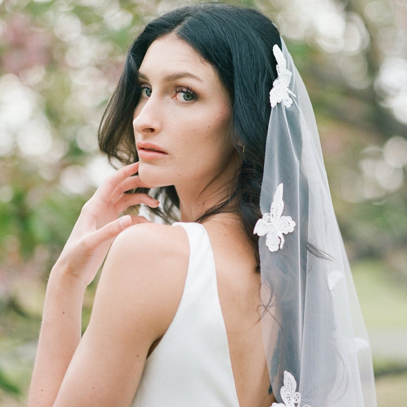 A bride looks over her shoulder; her butterfly lace wedding veil flowing behind her. Canadian weddings. Wedding Canada. Wedding veils Canada. Bridal Hair Accessories. Bridal Accessories. Canadian Bridal Accessories. Handmade Canadian Accessories. Canadian handmade Accessories. Canadian designer. Canadian artist.