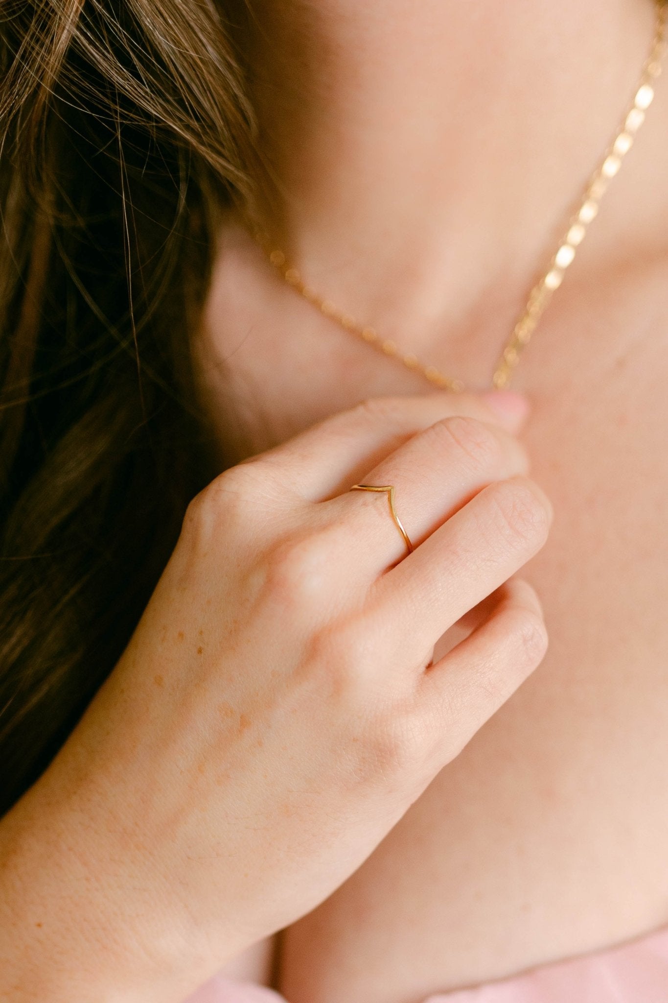 Hand touching gold necklace wearing peaked gold-filled ring with V-shape design. Canadian jewelry business. Gold-filled Canadian jewelry.