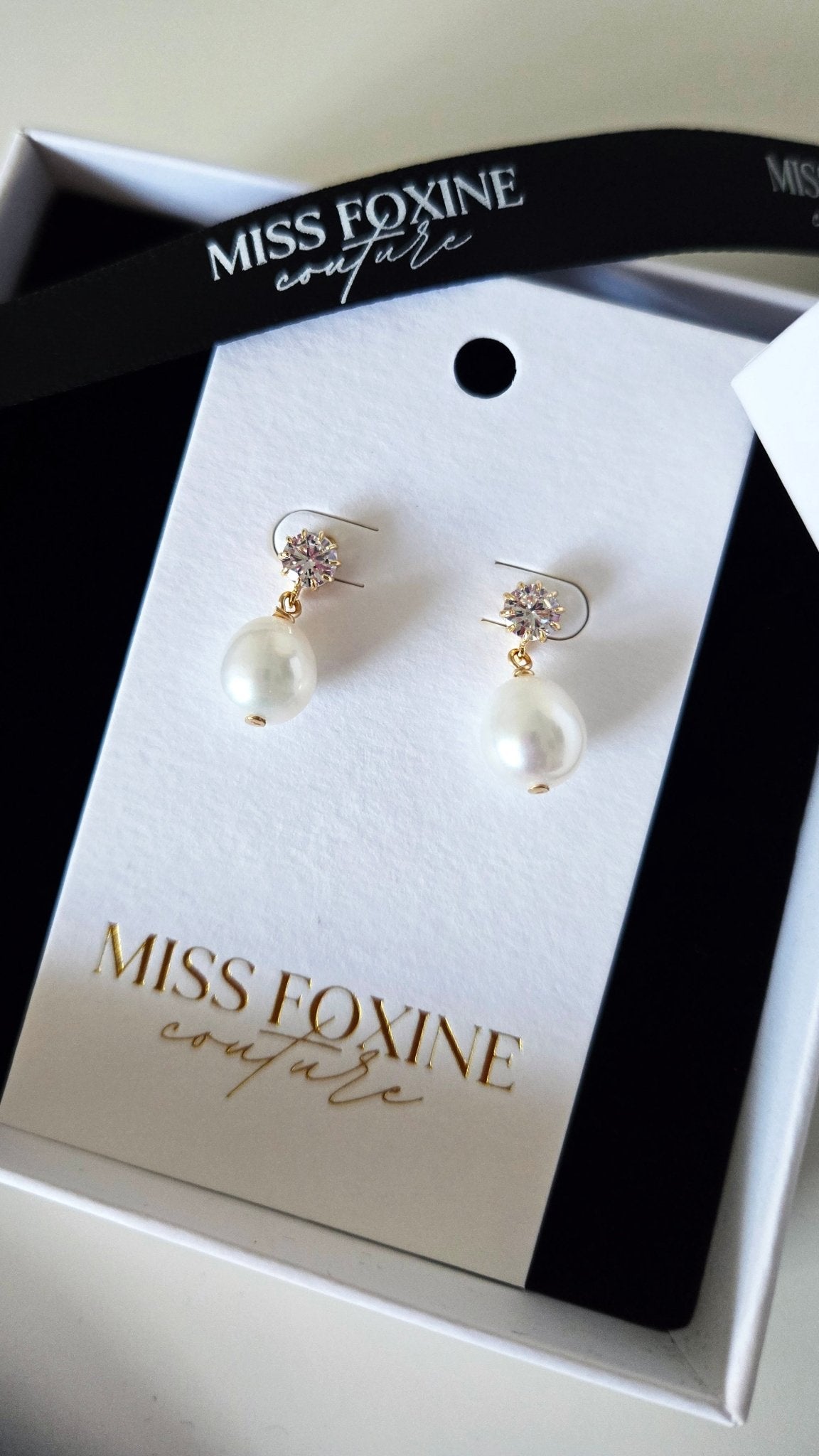 A pair of freshwater pearl earrings with crystals on a Miss Foxine card sitting in a black and white box with a white background. Pearl bridal earrings, bridesmaid earrings, & pearl bridesmaid jewelry handmade by Canadian BIPOC jewelry designer