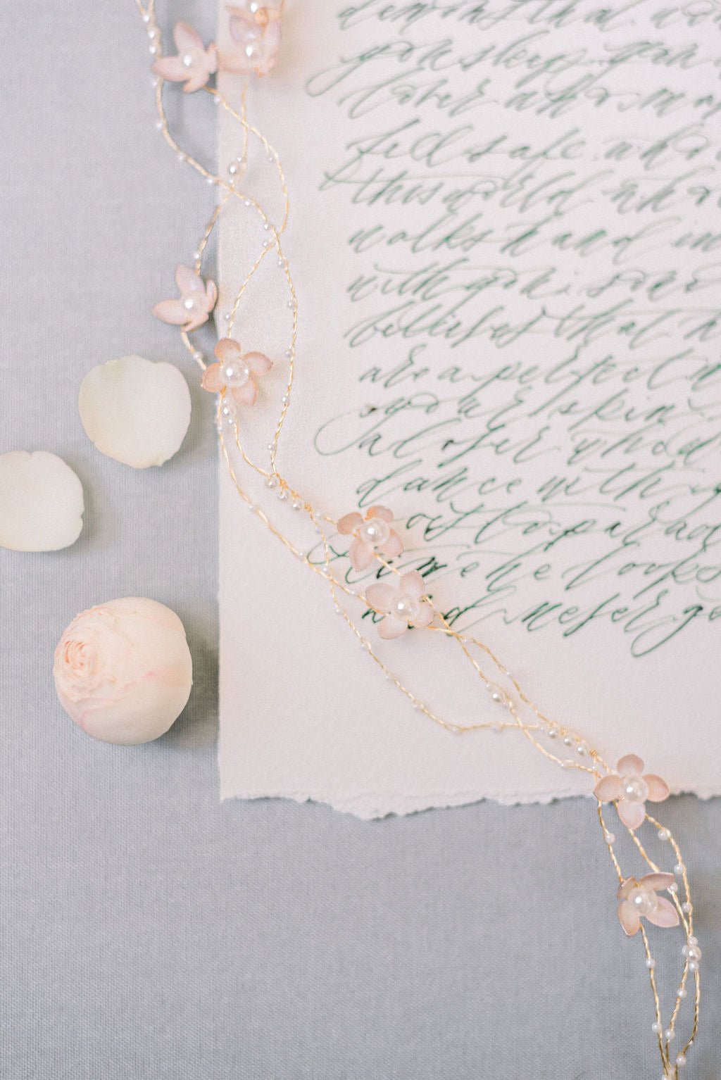 Decorative floral bridal hairvine with freshwater pearls on a piece of paper with cursive writing with pale grey background. Bridal jewelry for Canadian weddings. Bridal hair accessories & wedding hair accessories handmade by BIPOC bridal designer