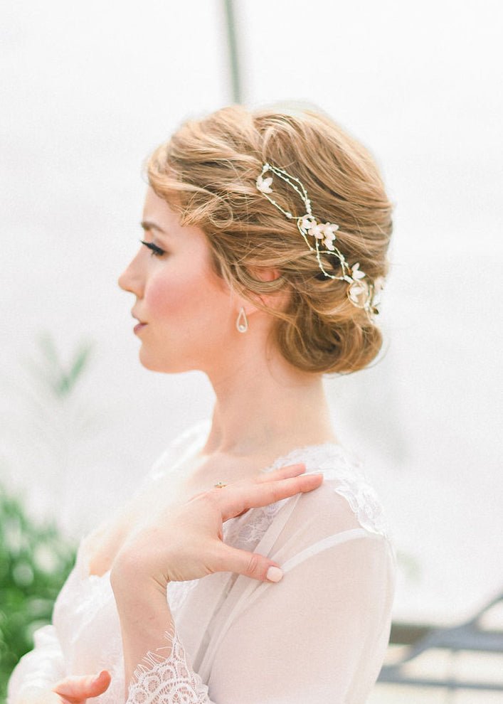 Bride in a sheer white wedding gown with blonde styled bridal hair-do wearing a delicate freshwater pearl and floral bridal headpiece on white background. Bridal jewelry, bridal hair accessories, & pearl bridal accessories handmade by Canadian BIPOC designer