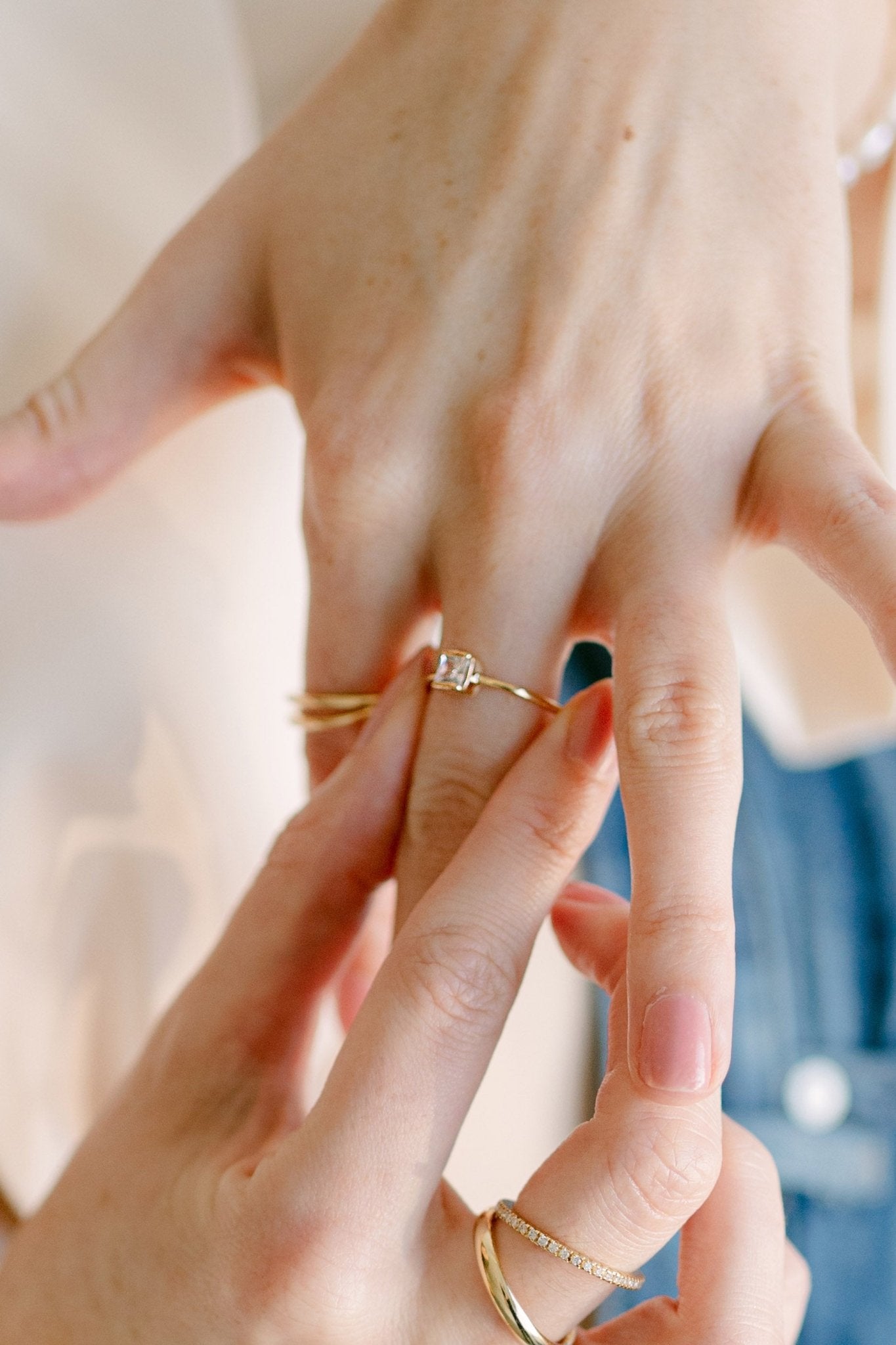 A gold-filled ring with square cubic zirconia crystal being put on a finger. Canadian handmade jewelry. Small Canadian jewelry brands.