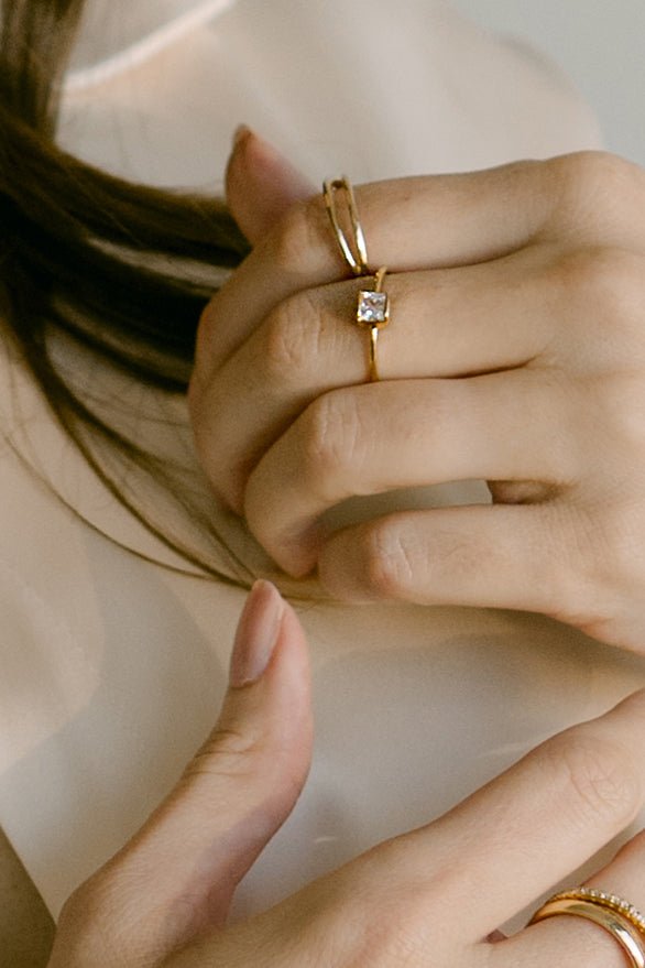 Close up of hand wearing 2 gold-filled rings. Minimalist Jewelry. Affordable engagement rings. Canadian jewelry brand.