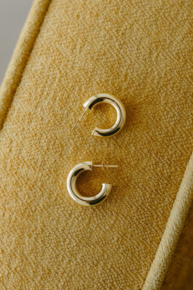 A pair of puffy gold-filled hoop earrings on textured background. Statement jewelry. Canadian handmade jewelry. Canadian jewelry maker.