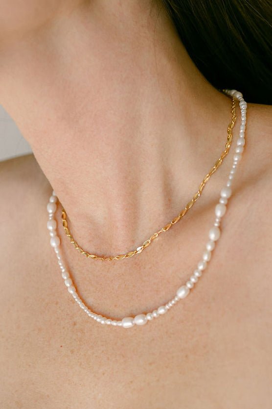 A neck with serpent link chain in 18k gold-fill stacked with organic freshwater pearl string necklace. Pearl jewelry Canada. Canadian jewelry brands.