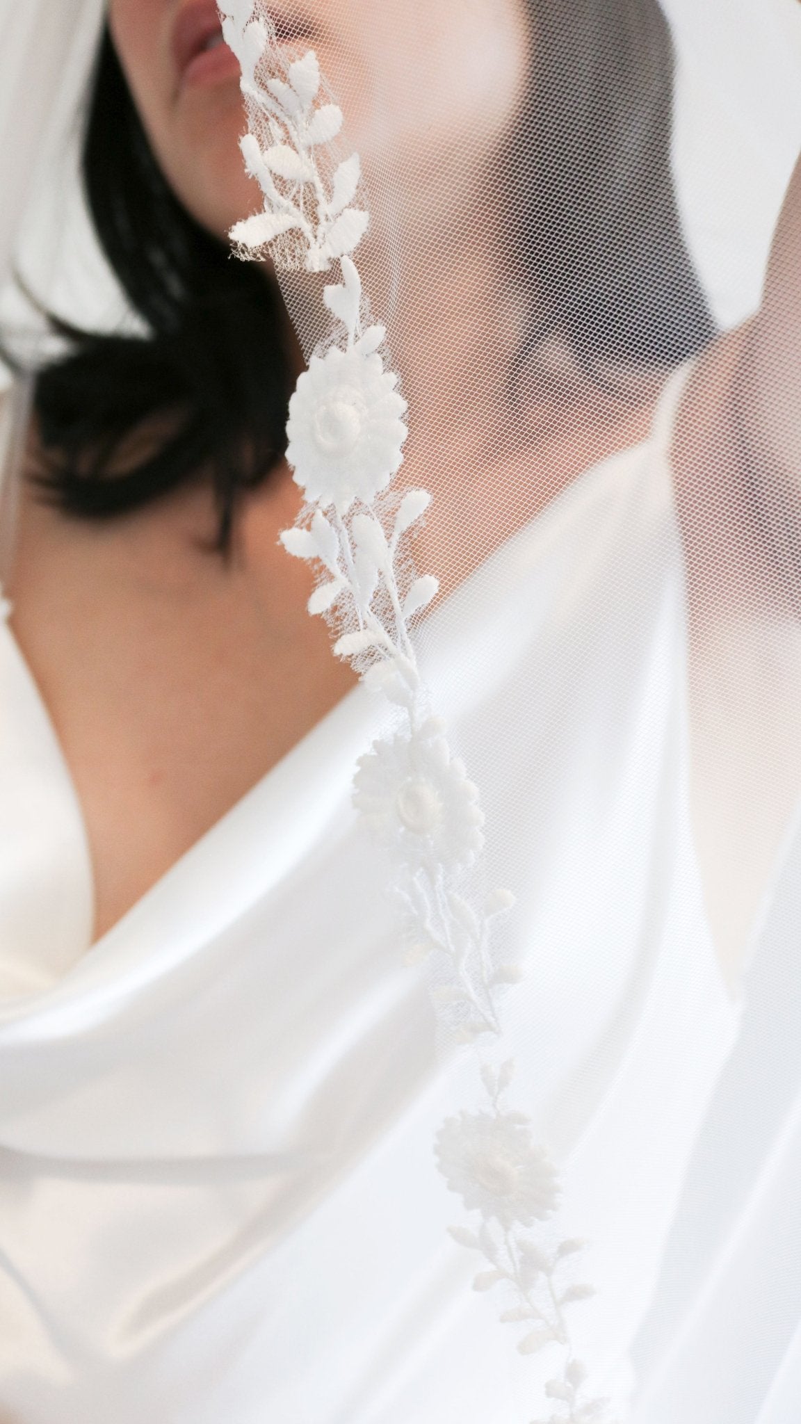 Woman holding up flower lace trim of Sienna Floral Vine Wedding Veil. Canadian weddings. Wedding Canada. Wedding veils Canada. Bridal Hair Accessories. Bridal Accessories. Canadian Bridal Accessories. Handmade Canadian Accessories. Canadian handmade Accessories. Canadian designer. Canadian artist.