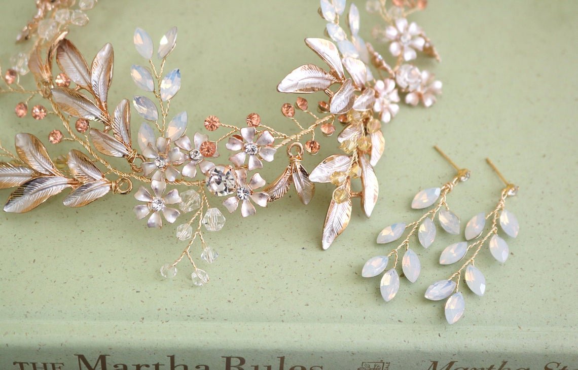 A Gold and crystal, enamel floral and leaf bridal hairvine sits on top of a stack of books next to a set of gold-wire opalite earrings. Bridal Hair Accessories, handmade bridal accessories Canada