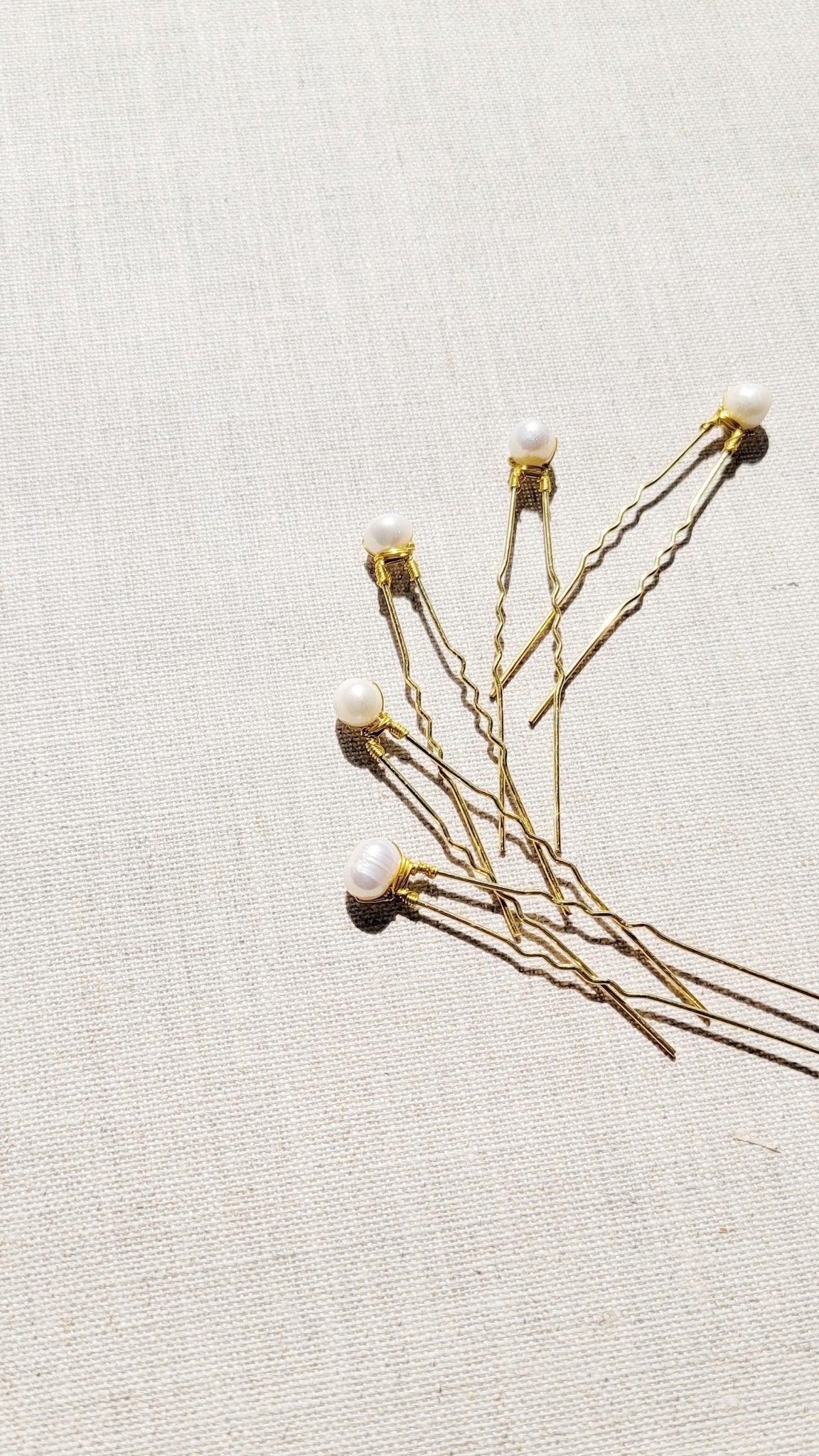 Several Tess Fresh Water Pearl Bridal Hairpins on a fabric background. Organic pearl jewelry. Bridal jewelry Canada. Pearl jewelry Canada. Pearl Bridal jewelry Canada.  Canadian jewelry maker. Canadian bridal jewelry. Bridal hair accessories. Bridal accessories.