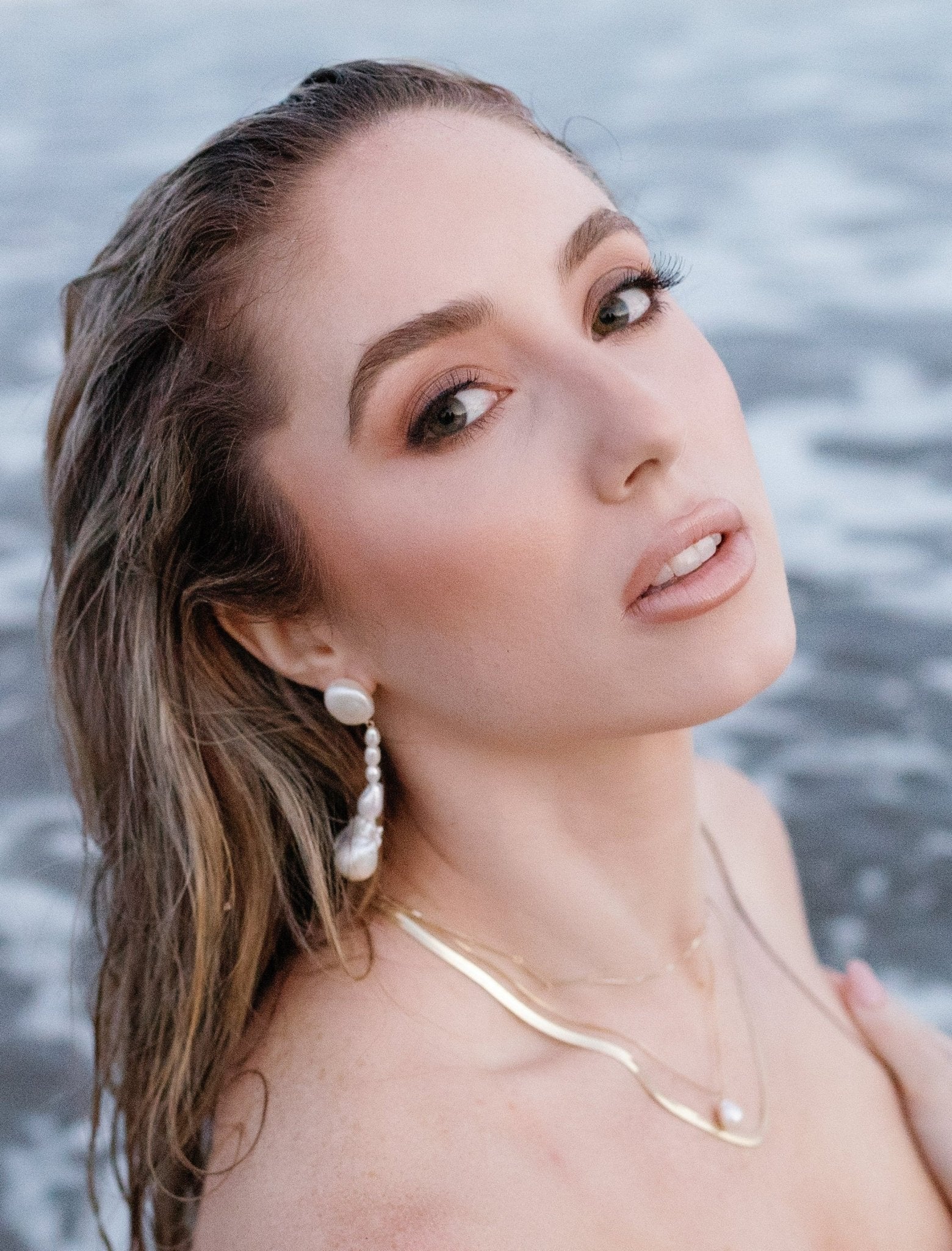 Ocean goddess wearing organic freshwater pearl earrings and multiple gold-filled necklaces. Gold-filled Canadian jewelry, Organic pearl jewelry, & handmade Canadian jewelry by BIPOC jewelry designer
