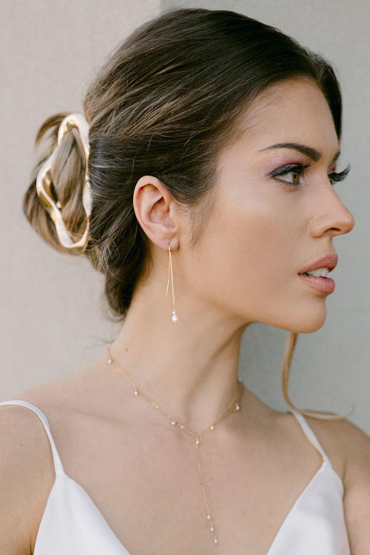 Minimalist bride wearing a gold claw hair clip, pearl threader earrings, and dainty pearl gold lariat necklace on white background. Minimalist bridal accessories, handmade hair accessories, everyday hair accessories Canada