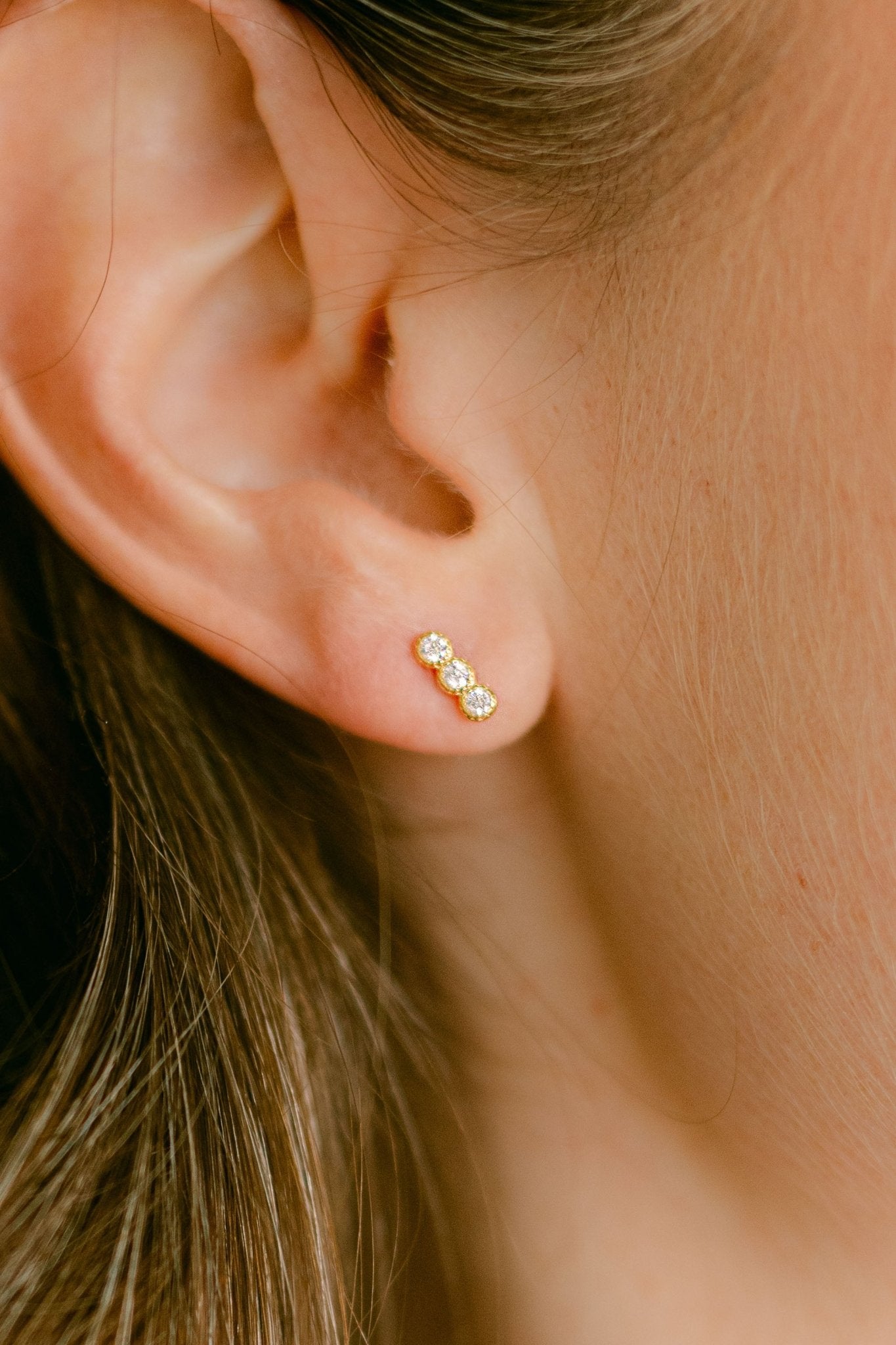 Close-up of an ear wearing a 3 crystal gold-filled stud earring. Everyday jewelry. Canadian handmade jewelry. Small Canadian jewelry brands.