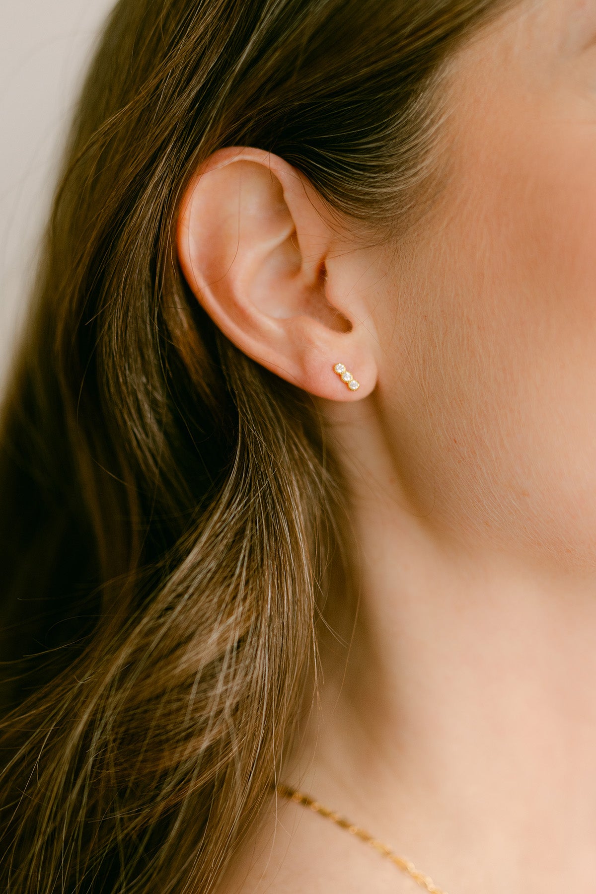 Close-up of an ear wearing a gold-filled earring with crystals. Gold-filled Canadian jewelry. Canadian jewelry brands. Everyday jewelry.