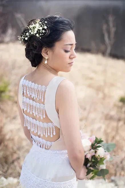 Dark haired BIPOC bride wearing handmade white lace wedding dress with flower bouquet & flowers in bridal up-do