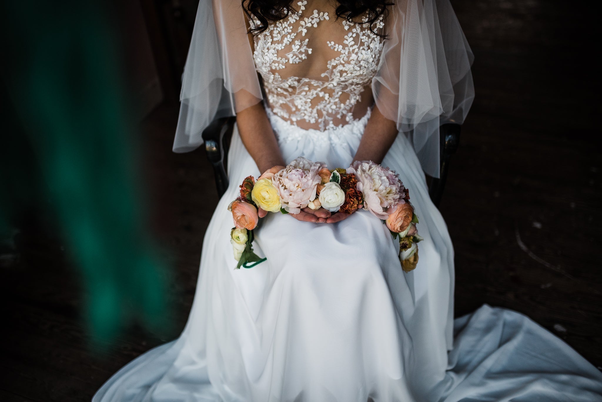 Bride in sheer lacy wedding dress holding large bridal crown with real flowers.