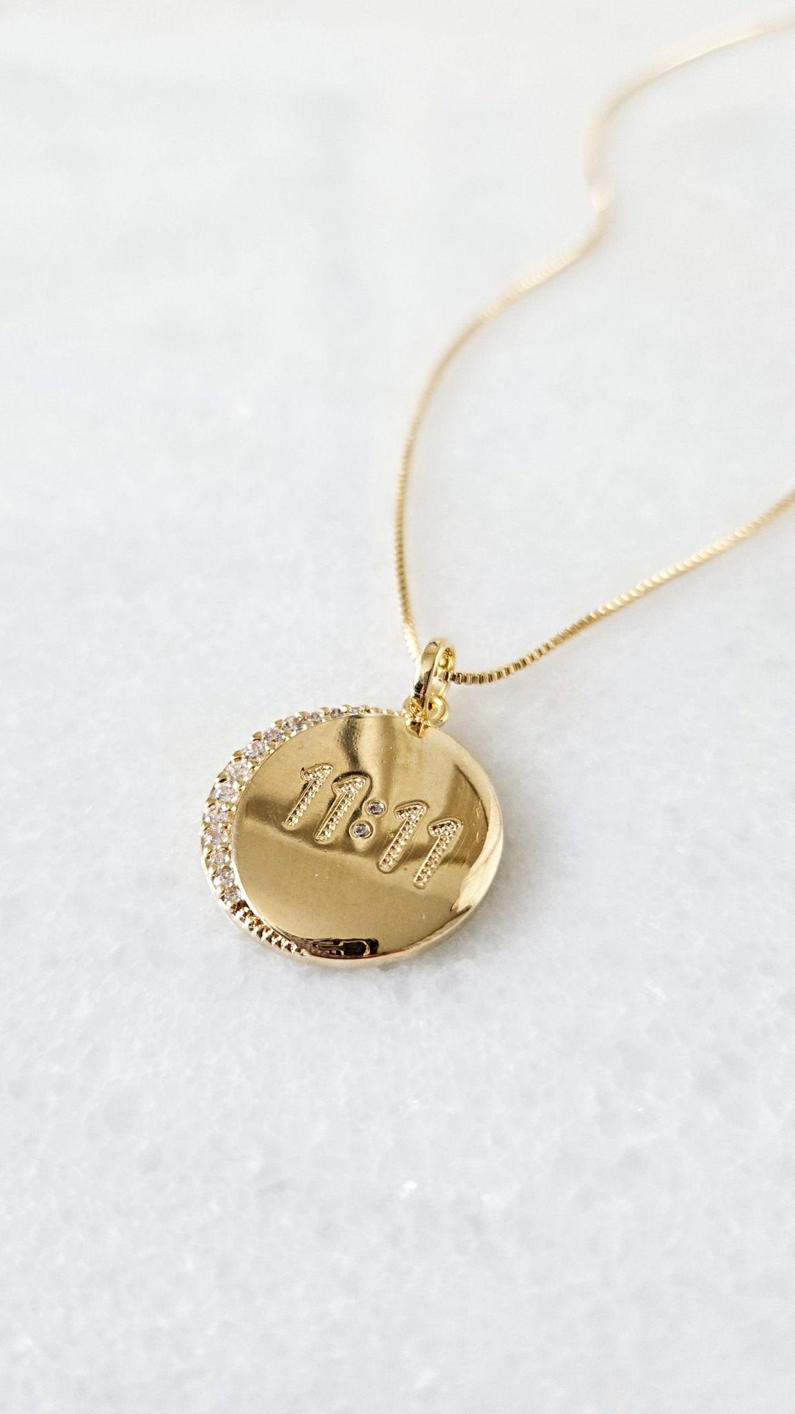 A round pendant with 11:11 and crystals hang on a gold-filled chain.