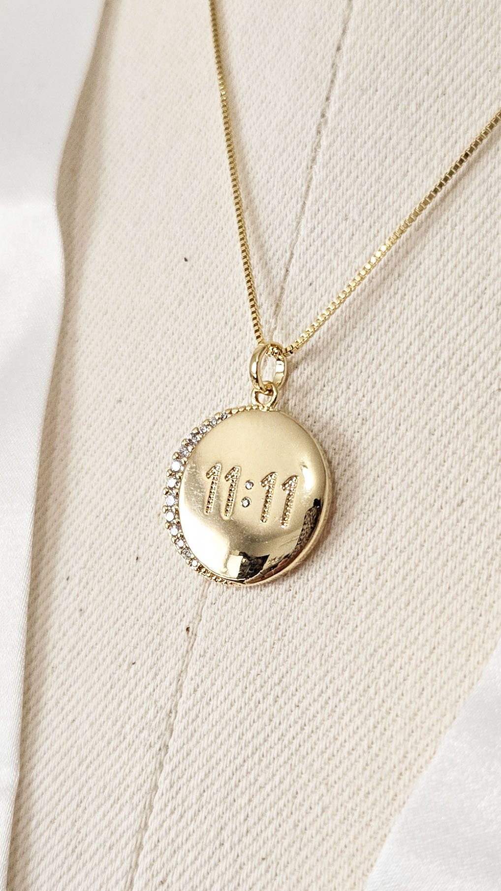 A close up of a gold-filled pendant with crystals and 11:11 angel number. 