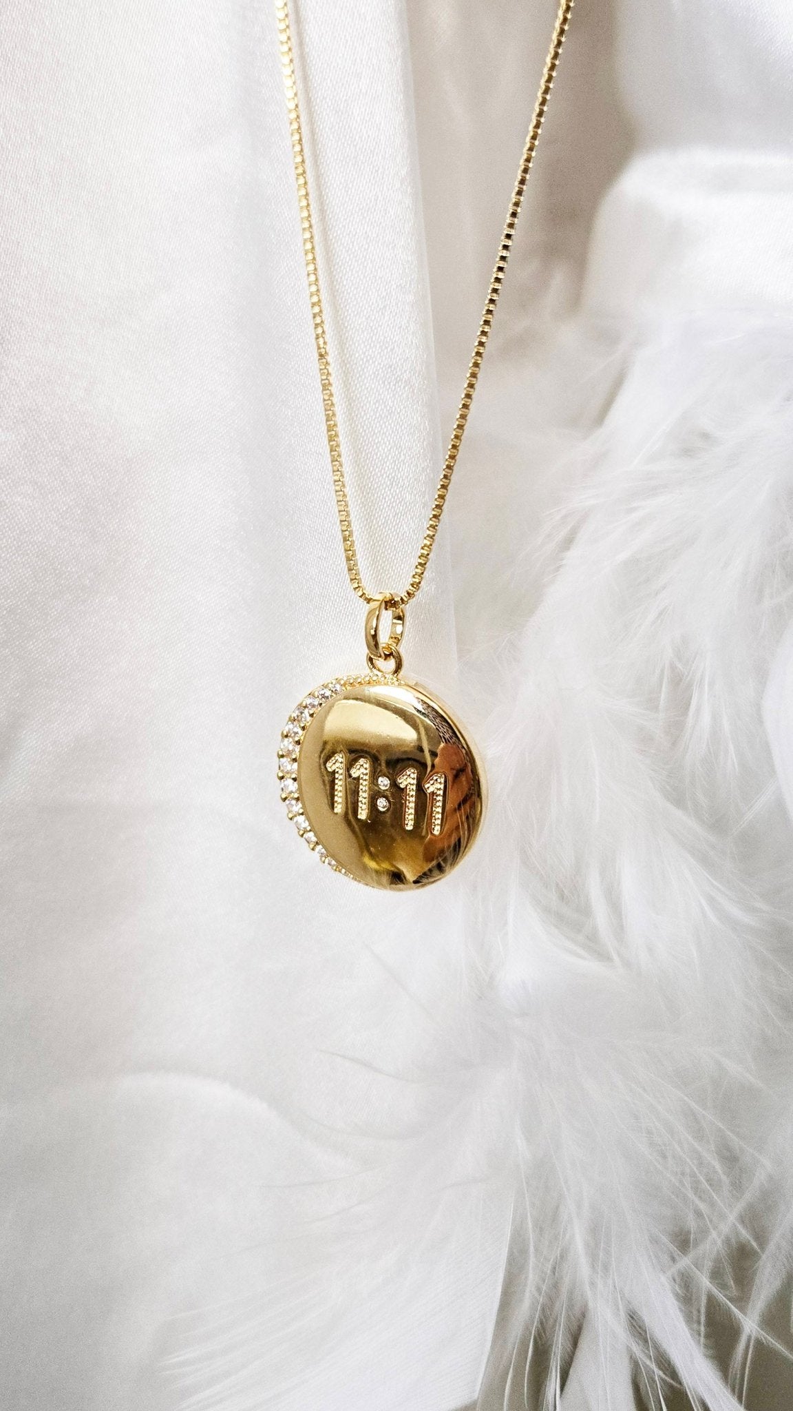 A gold-filled necklace with a gold and crystal pendant that says 11:11.