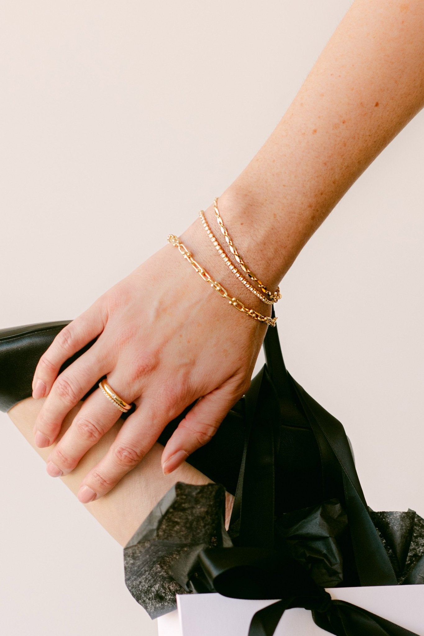 Hand with gold ring and bracelet stack holding foot. Canadian jewelry brand. Gold jewelry Canada.