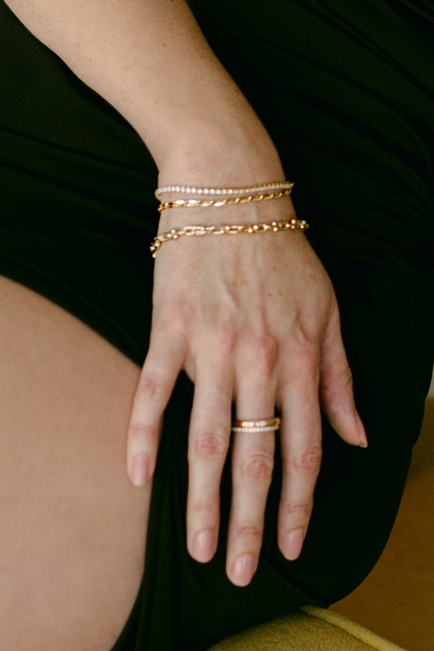 A set of 3 gold-filled bracelets on wrist and 2 gold rings. Canadian Everyday jewelry. Gold-filled jewelry.