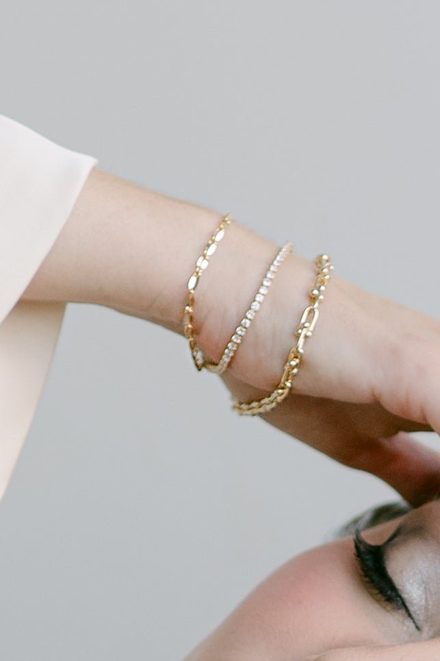 A stack of 3 gold-filled bracelets on a wrist with hardware U-link bracelet in the front. Modern jewelry designs & Everyday jewelry Canada.