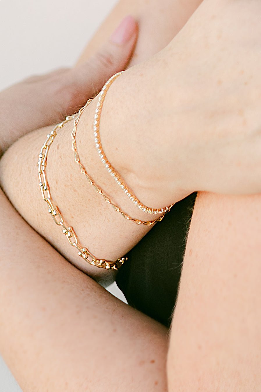 Close-up of a woman's wrist wearing multiple gold-filled bracelets. Modern jewelry designs, everyday jewelry, & Gold-filled jewelry Canada. Handmade in Canada by Canadian jewelry artist