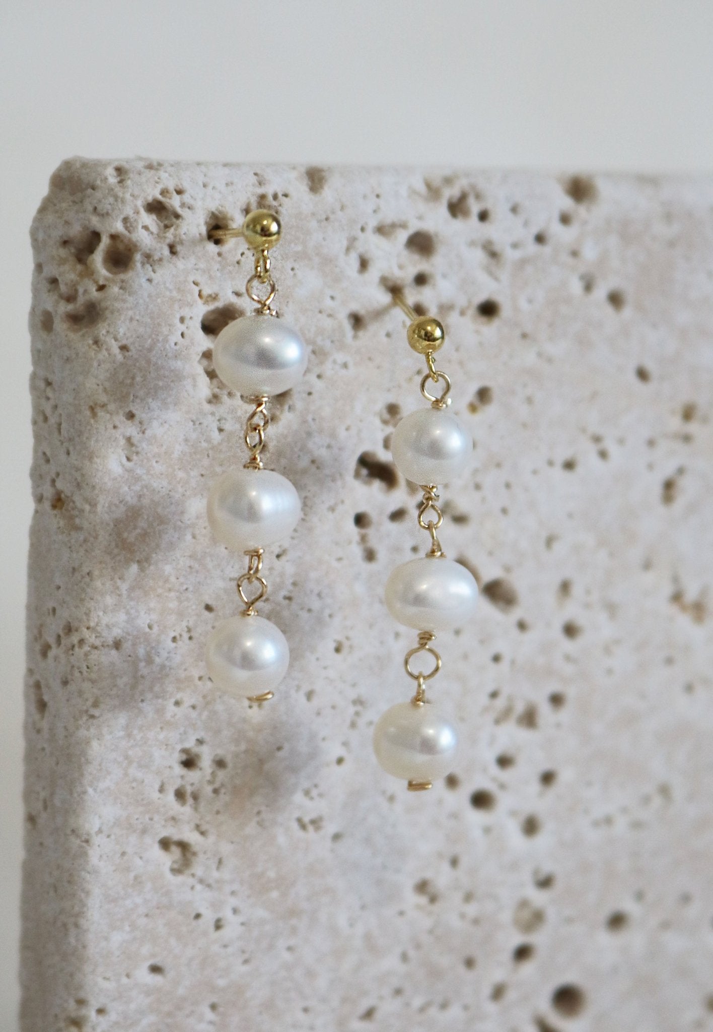 Gold Filled Isla Drop Fresh Water Pearl Studs Hang from a Stone.