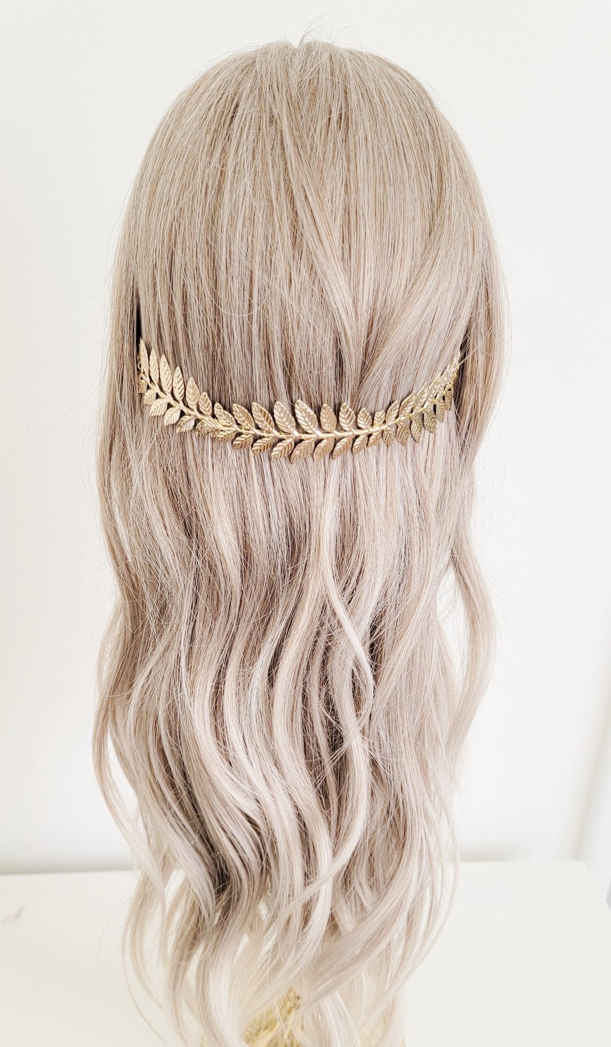 Gold-dipped laurel leaf headband against wavy locks. 