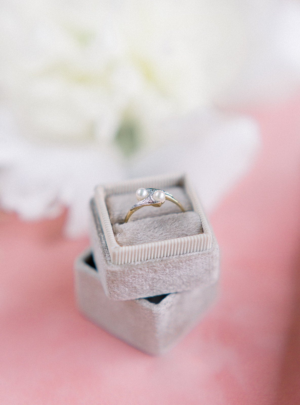 The front view of a Double Pearl and Diamond Vintage Engagement Ring in 9k Yellow White Gold sitting in a beige ring box stack.