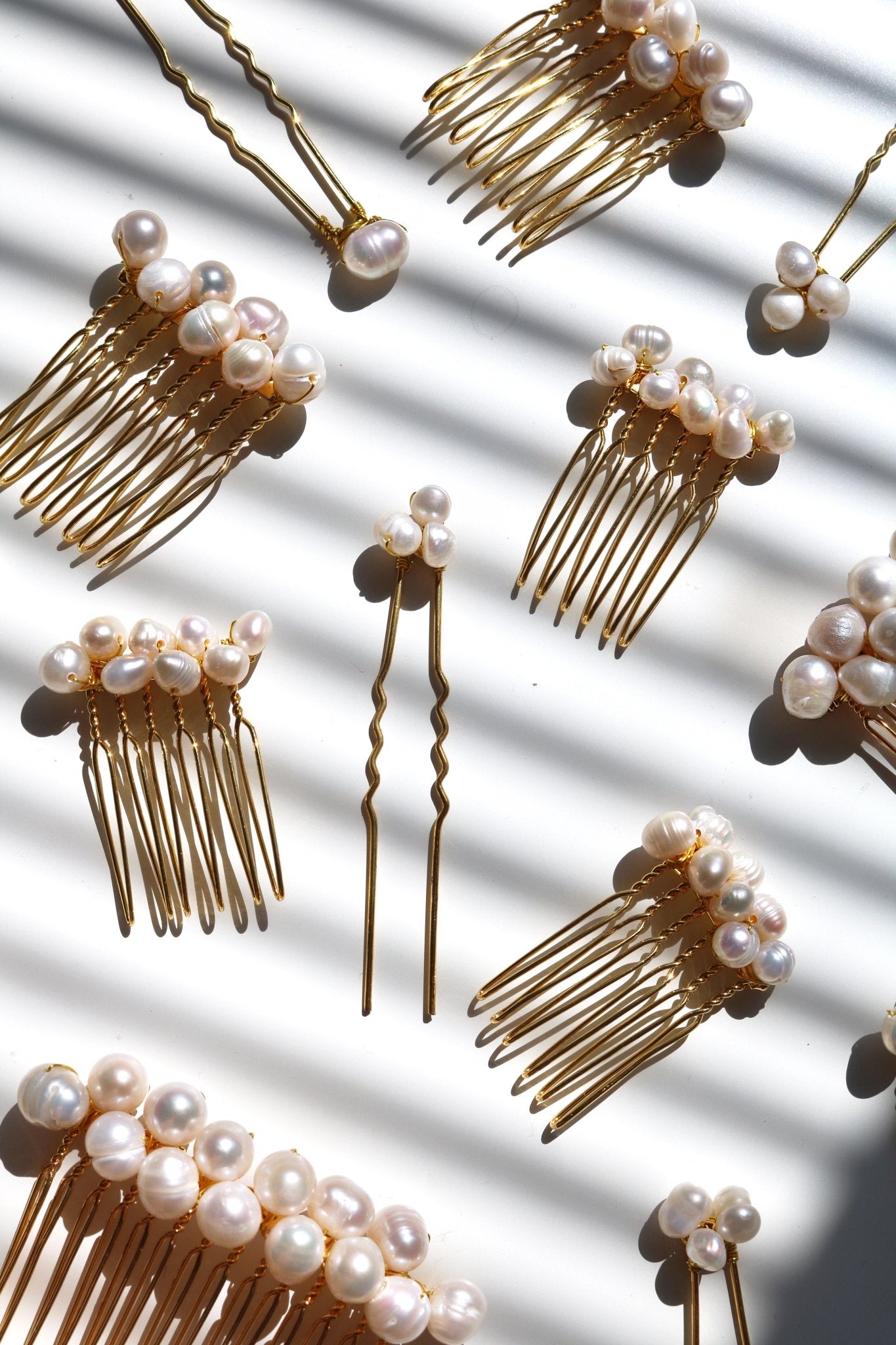 Multiple golden bridal hair combs and hair pins with clustered freshwater pearls on white background. Organic pearl accessories designed by Canadian jewelry maker for affordable bridal hair accessories. 