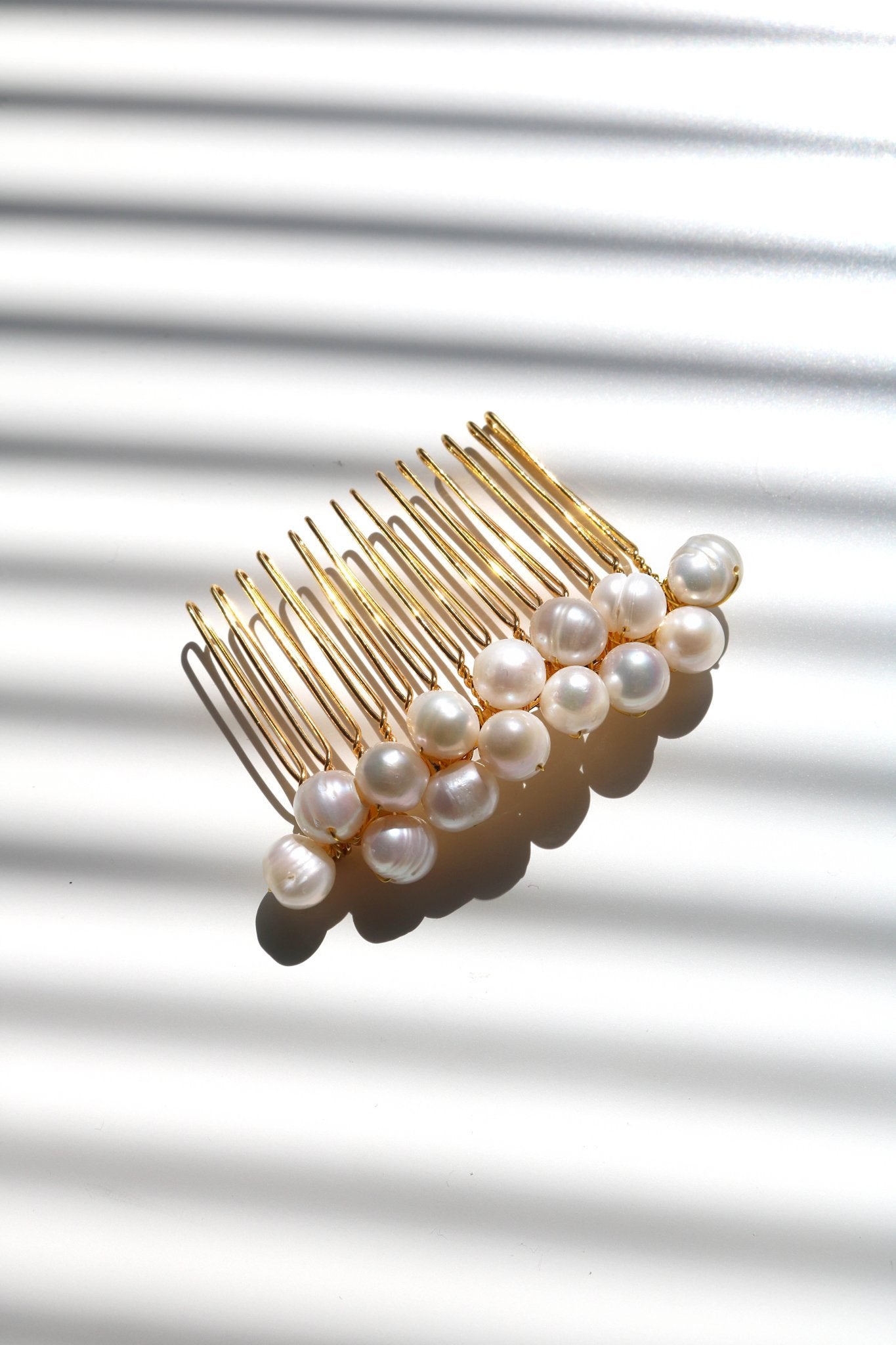 Gold bridal hair comb with freshwater pearls on a white background. Designed & made by a Woman-owned Canadian jewelry brand as Bridal Hair Accessories.