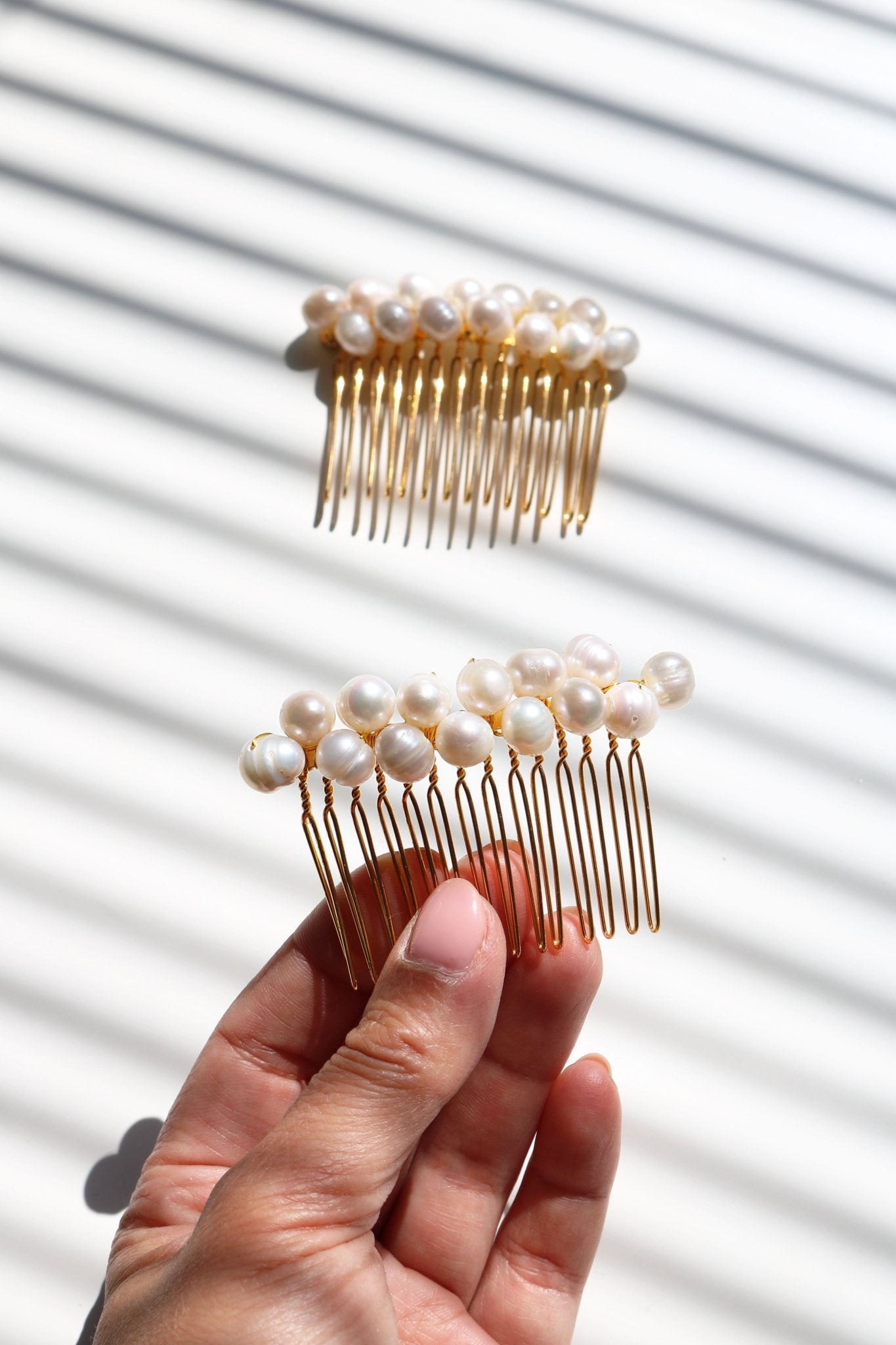 Two gold freshwater pearl bridal hair combs with white background and one being held up by a hand. Handmade Canadian jewelry for weddings: Pearl bridal hair accessories, affordable jewelry.
