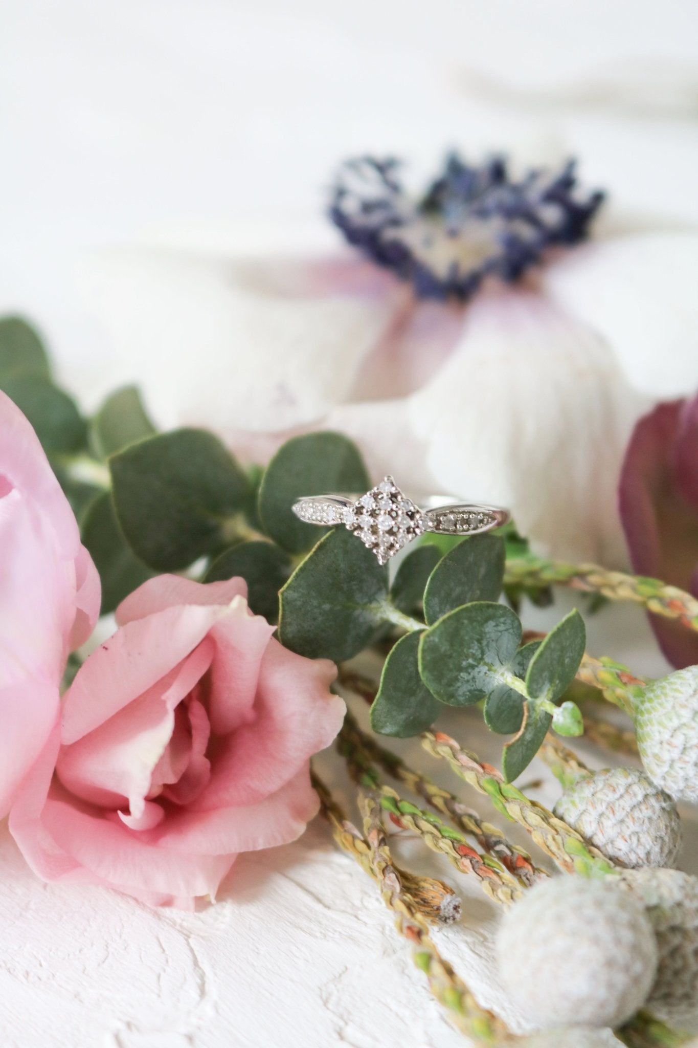 Vintage diamond engagement ring in 9ct white gold among a floral arrangement. 