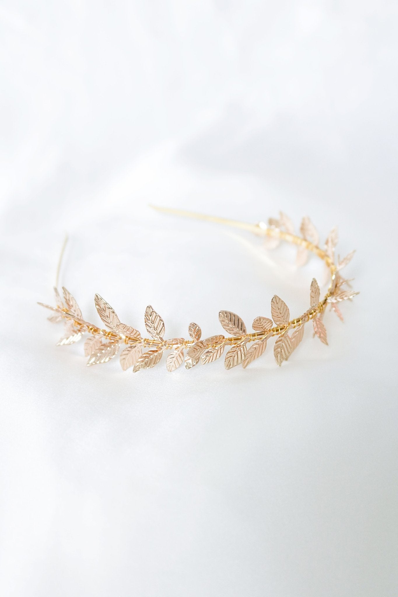 Gold pointed laurel leaf headband against white backdrop. 