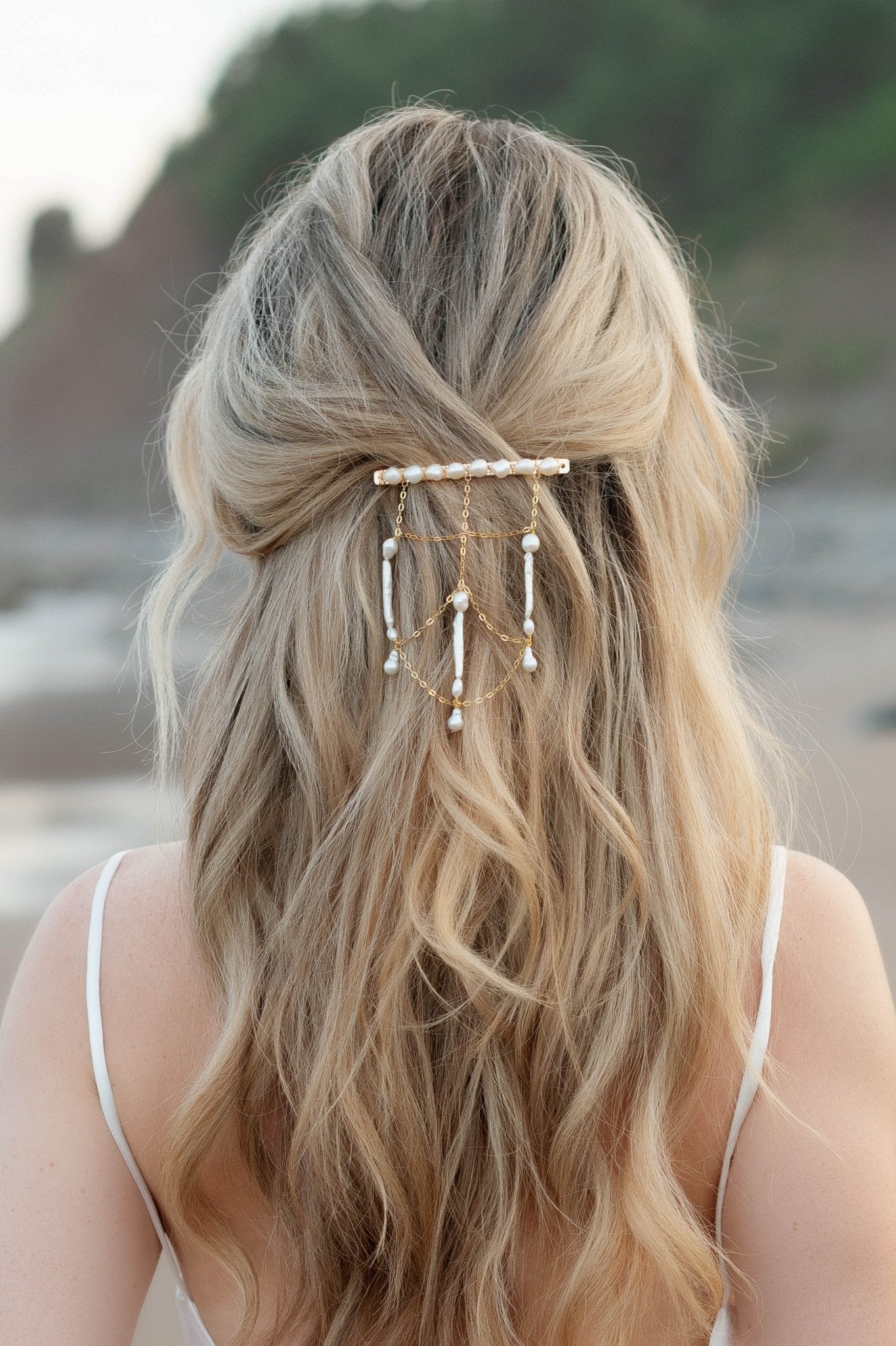 Golden netted hair chain and barrette with multiple freshwater pearls cascades down a wave of blonde hair. 