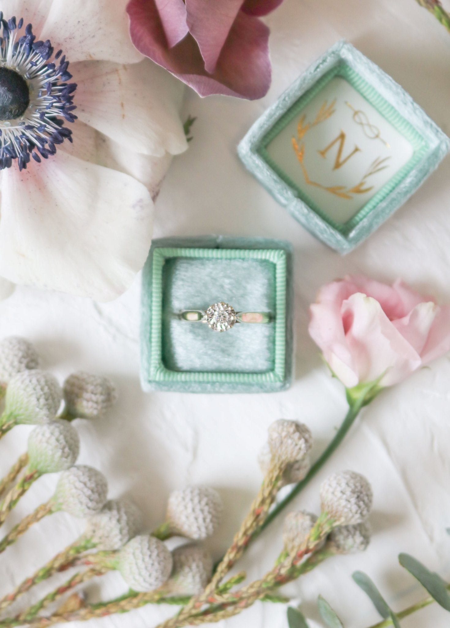 Antique Engagement Ring in 9ct Yellow and White Gold with Diamond displayed in a pale green ring box among flowers.