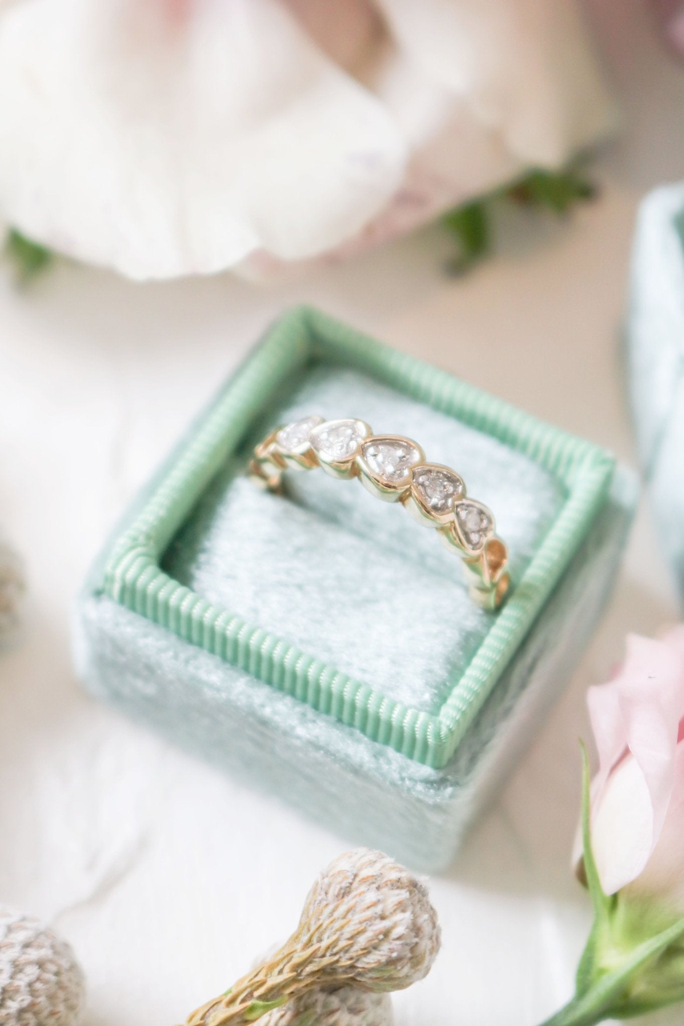 Gold engagement ring with diamond hearts in a ring box.