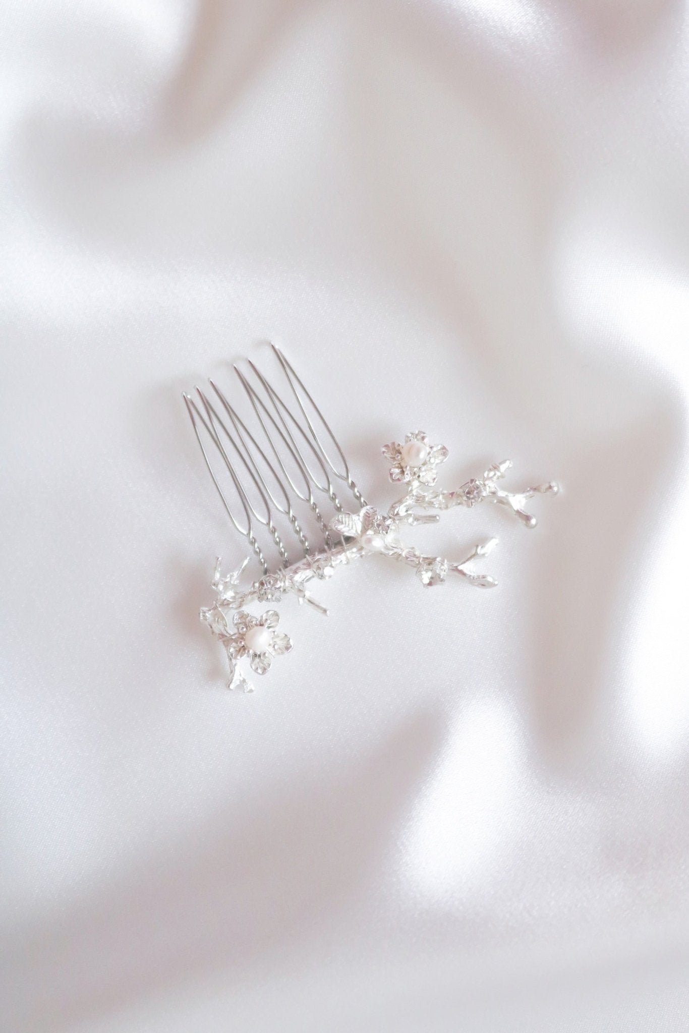 Anthea silver comb for bridal hair accessories with freshwater pearls on white satin sheet.