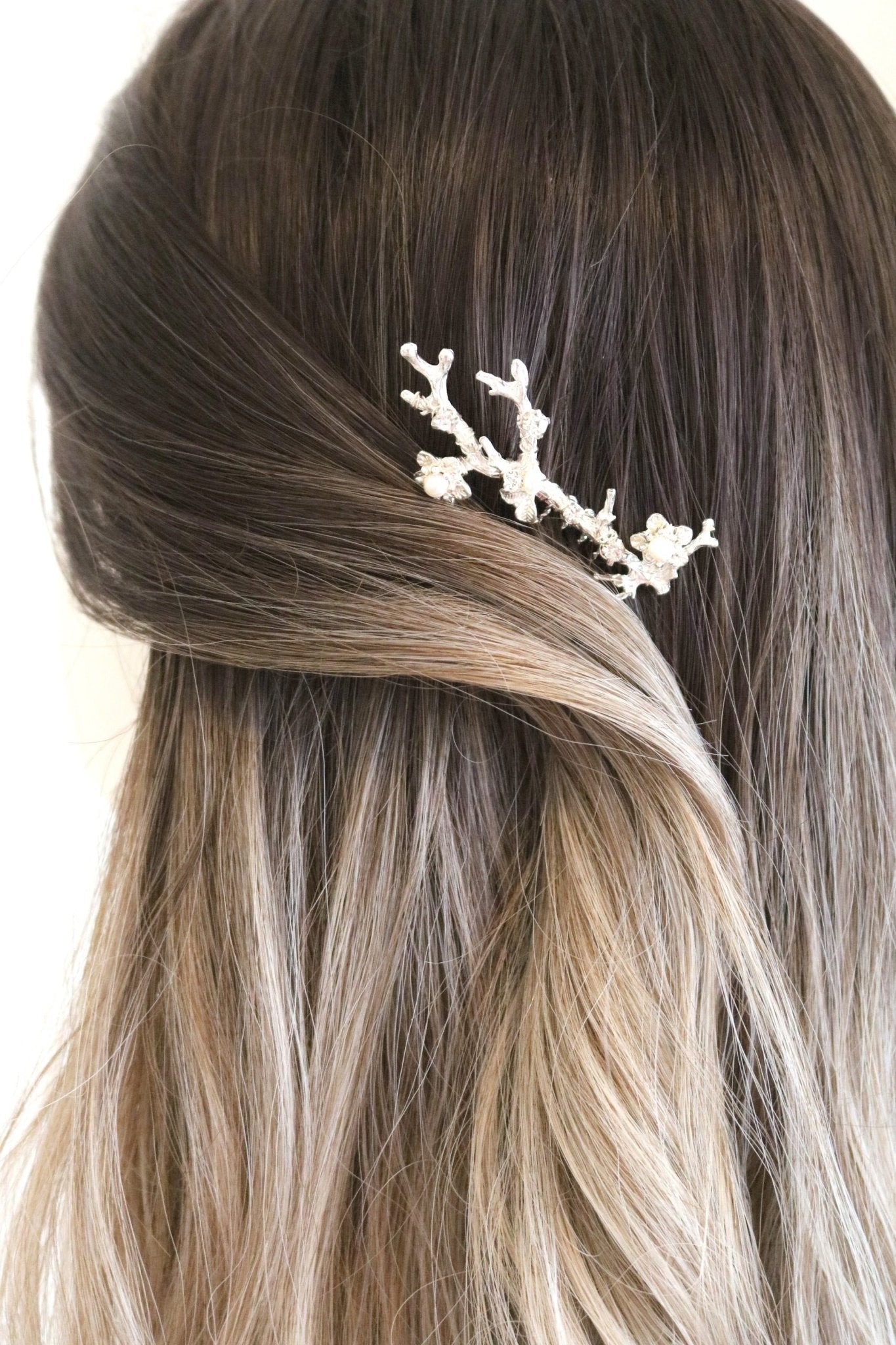 Silver bridal hair comb with pearls holding hair back. 