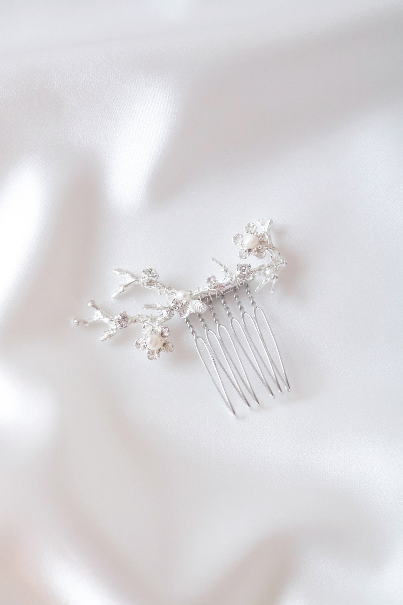 Anthea silver comb for bridal hair accessories with freshwater pearls on white satin sheet.