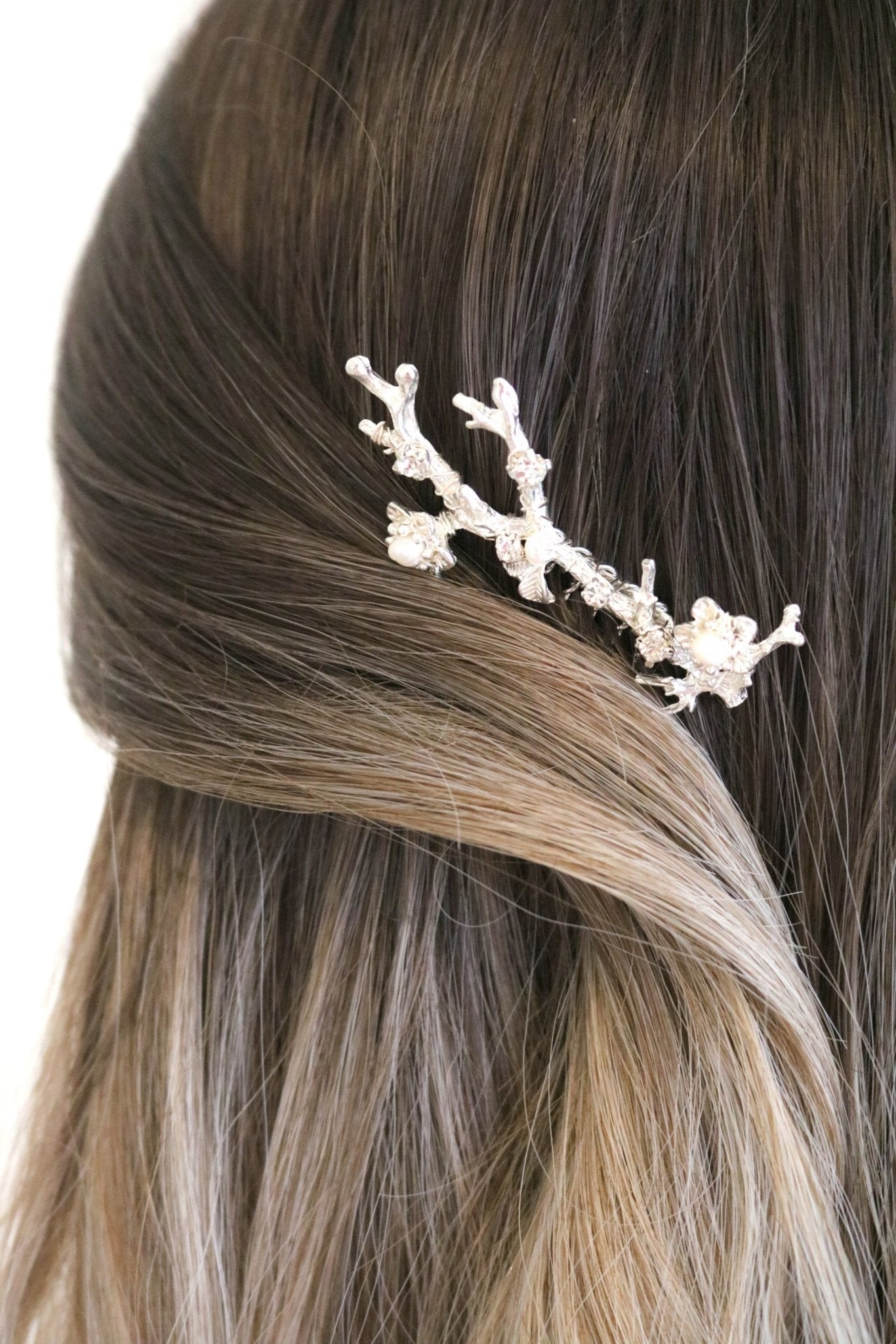 Silver bridal hair comb with pearls holding hair back. 