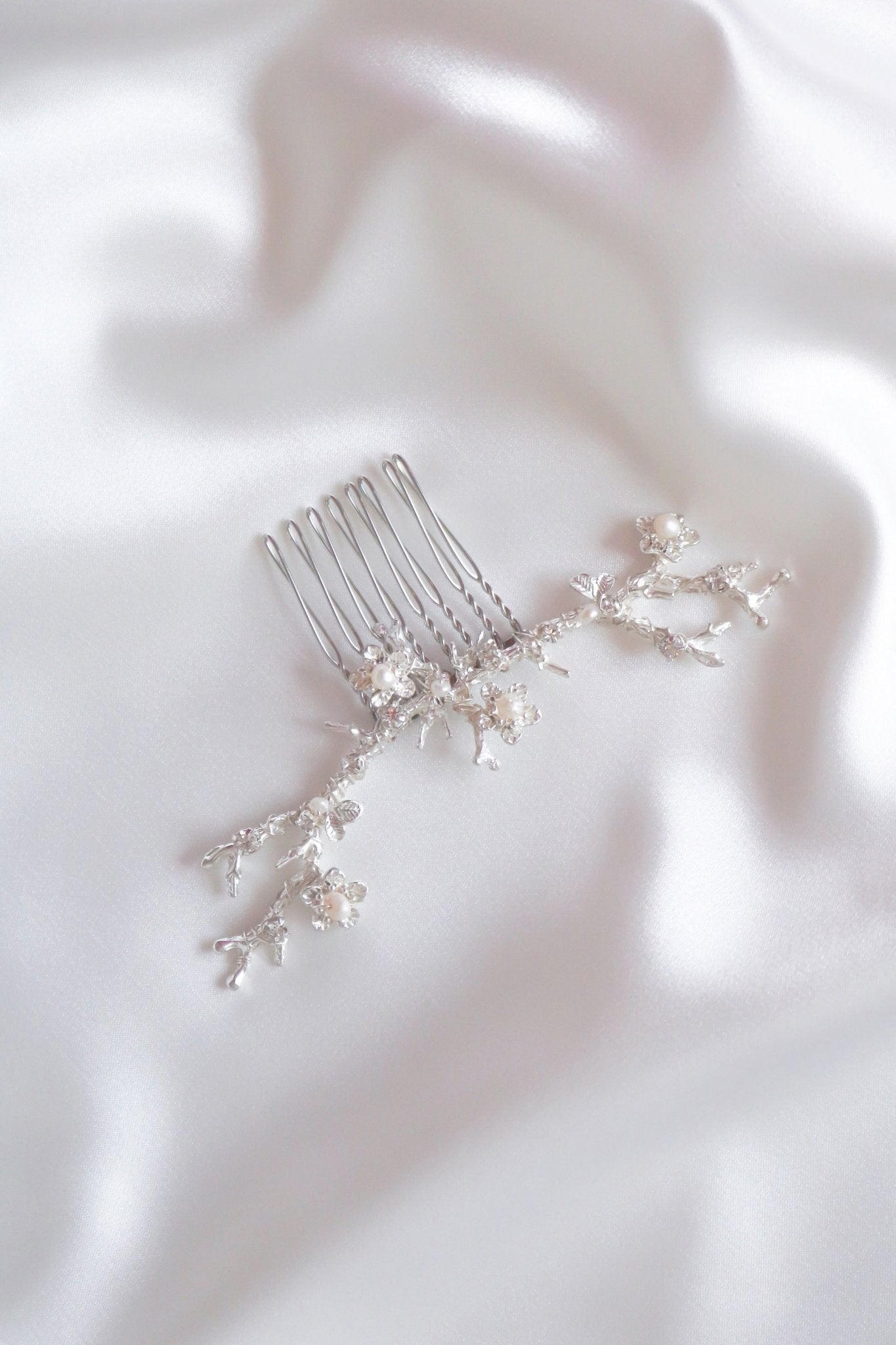 Anthea wide bridal hair accessory silver floral hair comb on white satin sheet. 