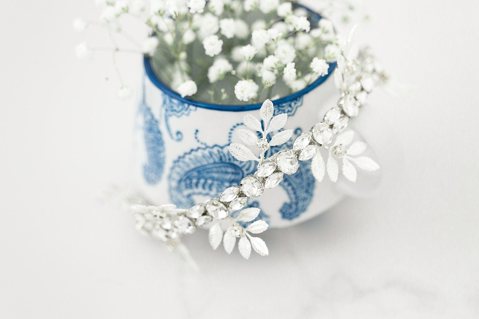 Anwen Crystal & Leaf Crown in Silver Placed Around a Flower Vase. Bridal Jewelry for a Stunning Bride. Bridal Hair Accessories. Bridal Accessories. Canadian Bridal Accessories. Handmade Canadian Accessories. Canadian handmade Accessories. Canadian weddings. Wedding Canada. 